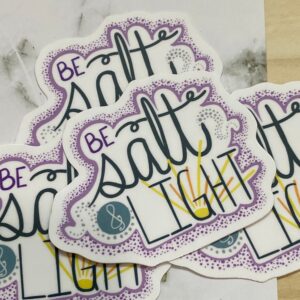 Stickers with the phrase Be Salt & Light in decorative lettering on marble and wood surface.