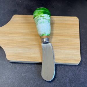 Small knife with a curved stainless steel blade and green-white handle on wooden board