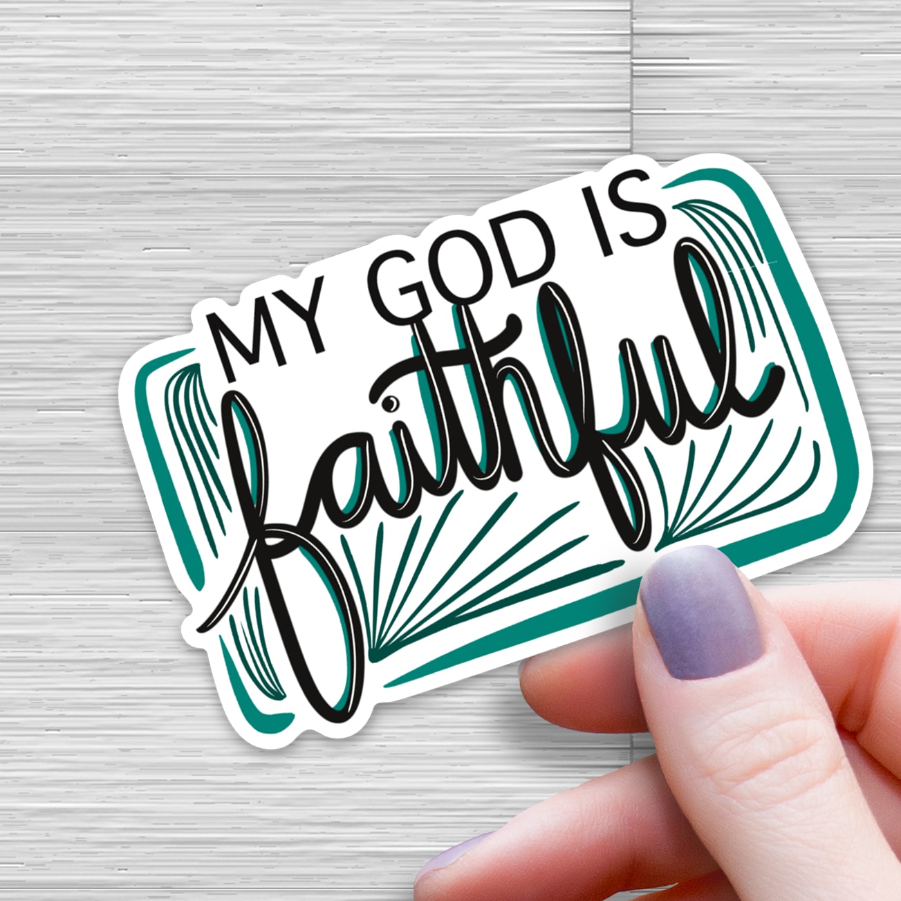 Hand holding “My God Is Faithful” Christian vinyl sticker with teal and black typography, faith-inspired waterproof decal for water bottles and laptops by Beth Ann Erickson Designs.
